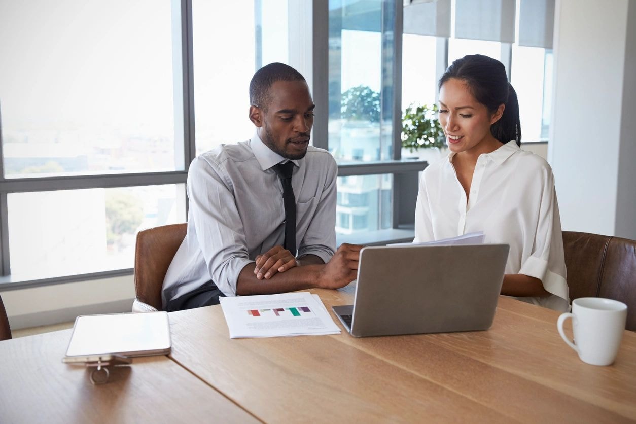 Business professionals collaborating over laptop in conference room
